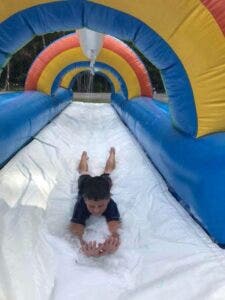 A child enjoying a rainbow inflatable splash and ride slide